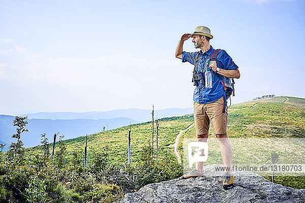 Mann bewundert die Aussicht auf die Berge während einer Wanderung