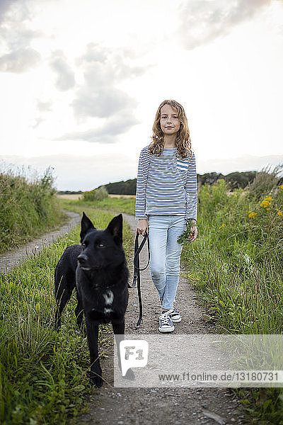 Mädchen mit einem Hund auf einem Feldweg stehend