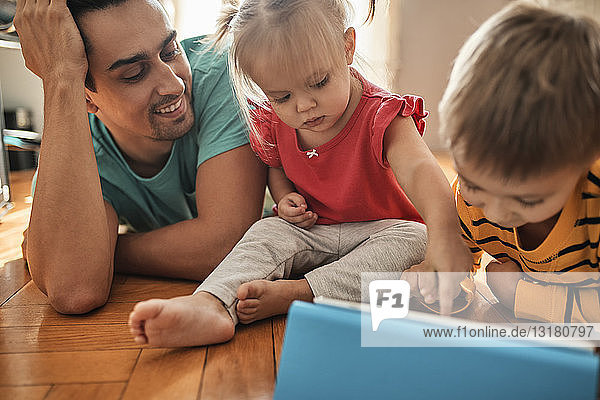 Vater und seine Kinder benutzen digitales Tablett zu Hause