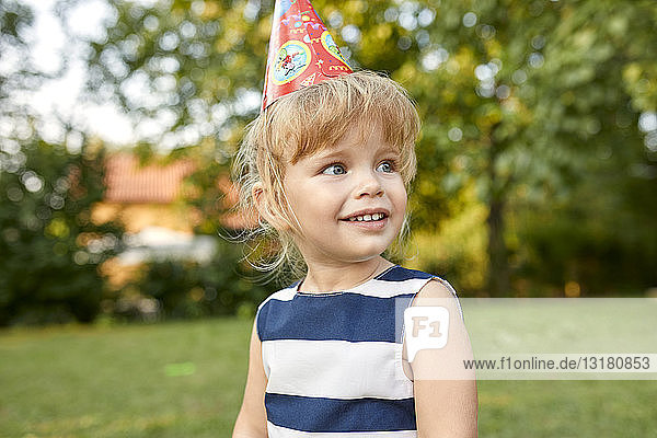 Porträt eines kleinen Mädchens auf einer Geburtstagsgartenparty mit Partyhut