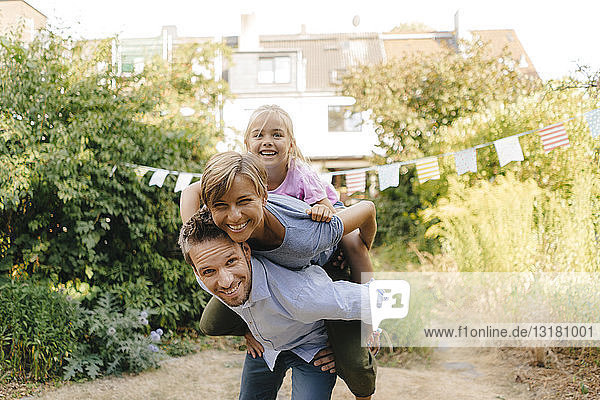 Glücklicher Vater trägt Familie huckepack im Garten