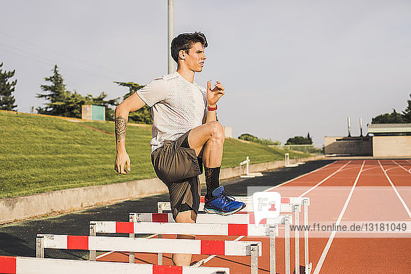 Athlete doing warm-up exercises on a tartan track for a hurdle race