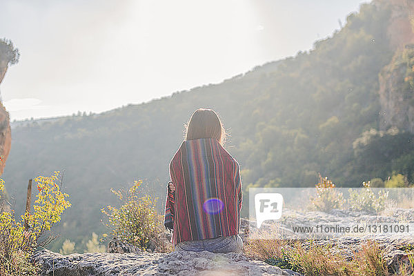 Spanien  Alquezar  Rückansicht einer auf einem Felsen sitzenden jungen Frau auf einer Wanderung