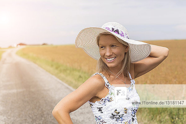Lächelnde reife Frau auf abgelegenem Feldweg im Sommer