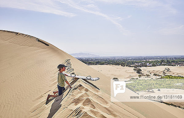 Peru  Ica  boy with sandboard on sand dune