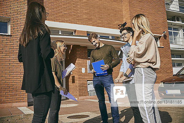 Gruppe glücklicher Studenten  die mit Dokumenten im Freien stehen