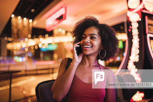 USA  Nevada  Las Vegas  Porträt einer glücklichen jungen Frau am Handy in einem Kasino
