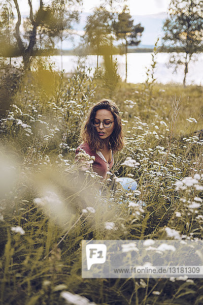 Junge Frau kauert in Blumenwiese