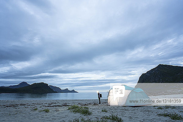 Norwegen  Lappland  Person mit Zelt an einem Strand am Fjord