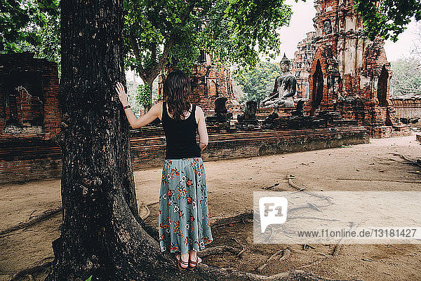 Thailand  Ayutthaya  Frau betrachtet eine Buddhastatue im Wat Mahathat
