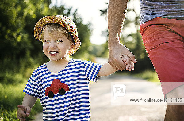 Porträt eines lachenden Kleinkindes  das auf der Hand des Vaters geht