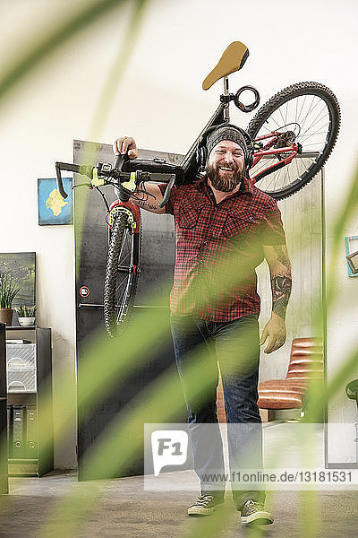Glücklicher Mann mit Kopfhörern und Fahrrad im Büro