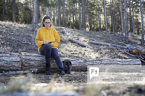 Young woman with yellow sweater in the forest  writing