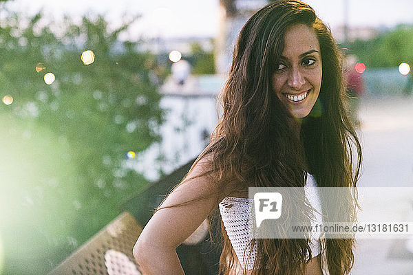 Porträt einer schönen lächelnden jungen Frau mit langen braunen Haaren im Freien