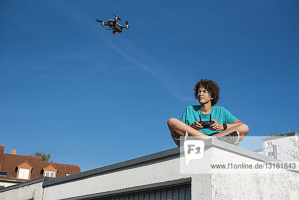 Boy navigating a flying drone sitting on garage roof