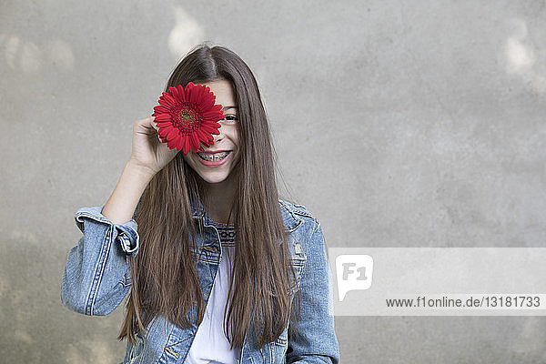 Bildnis eines lachenden Mädchens mit Blumenkopf aus roter Gerbera