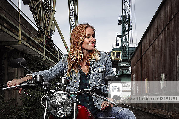 Porträt einer lächelnden jungen Frau auf Motorrad