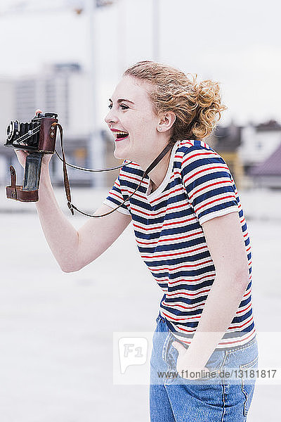 Porträt einer lachenden jungen Frau mit Oldtimer-Kamera