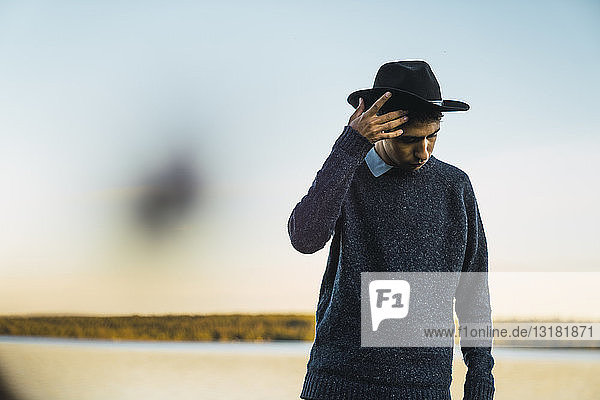 Portrait of a young man with hat at a lake