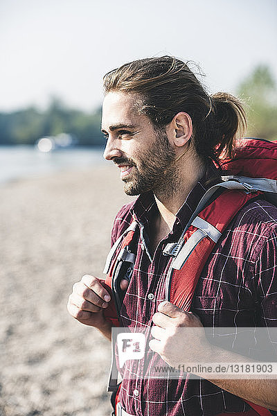 Lächelnder junger Mann mit Rucksack im Freien