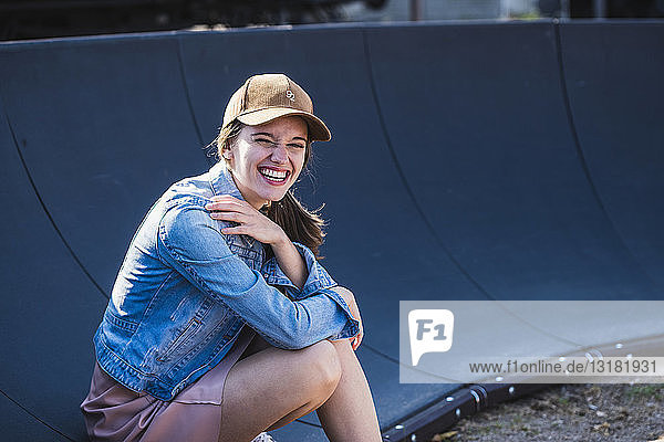 Porträt einer lachenden jungen Frau  die im Freien sitzt