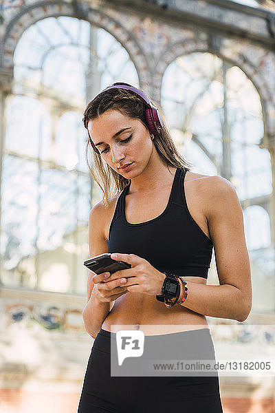 Fit young woman with a smartwatch  using smartphone