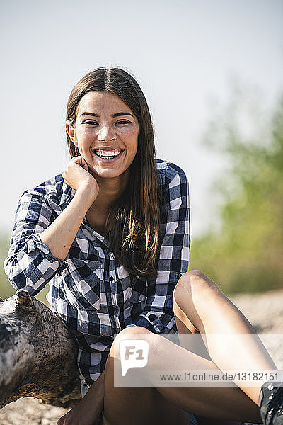 Porträt einer glücklichen jungen Frau  die im Freien sitzt