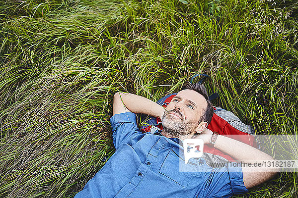 Relaxed man lying in grass enjoying hiking trip