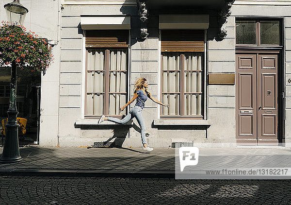 Niederlande  Maastricht  blonde junge Frau läuft an einem Gebäude in der Stadt entlang