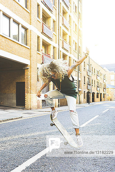 Junge Frau macht in der Stadt Tricks mit ihrem Skateboard