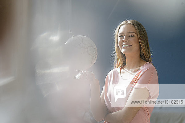 Porträt einer lächelnden jungen Frau mit Globus