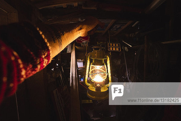 Hand holding storm lantern in a dark chamber