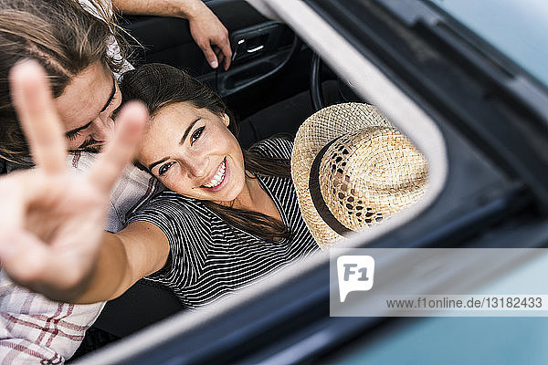 Glückliches junges Paar in einem Auto durch das Schiebedach gesehen