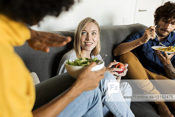 Freunde sitzen auf der Couch  unterhalten sich und essen