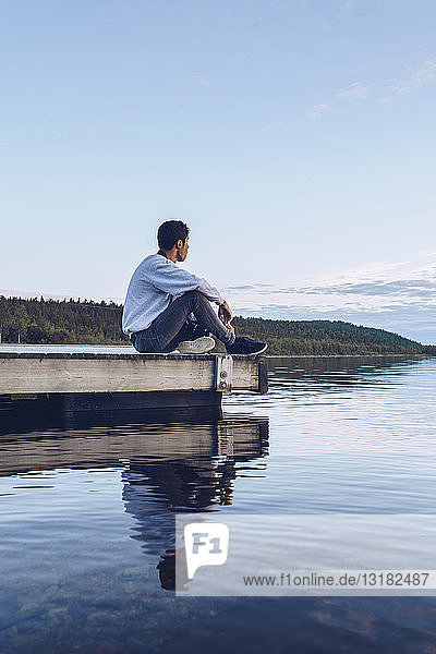 Junger Mann sitzt am Inari-See und schaut auf Aussicht  Finnland