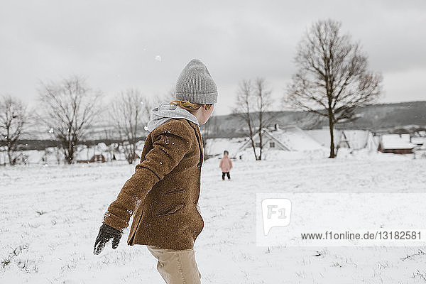 Boy and his little sister playing together in snow-covered landscape