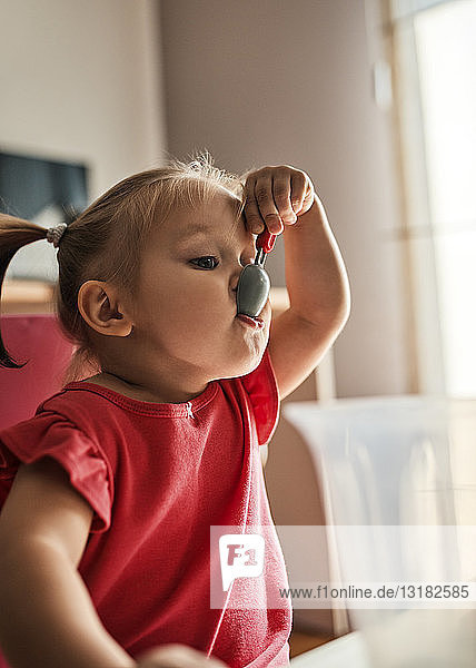 Porträt eines kleinen Mädchens  das mit einem Plastiklöffel spielt
