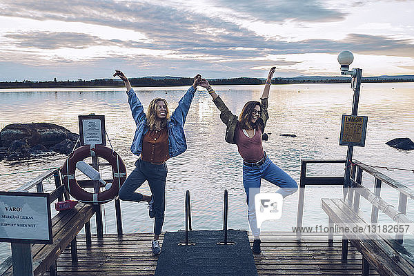 Zwei Freundinnen stehen auf einem Bein auf einem Steg am INari-See  Finnland