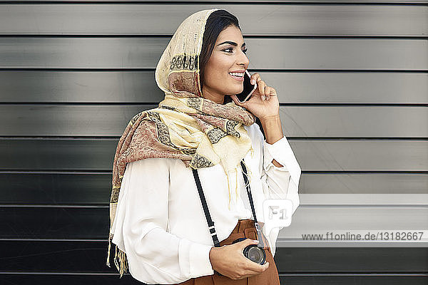 Spain  Granada  young Arab tourist woman wearing hijab  using smartphone