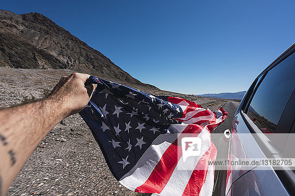 USA  Kalifornien  Death Valley  Männerhand hält neben dem Auto die amerikanische Flagge