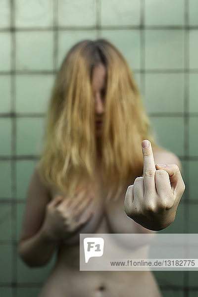 Nackte Frau zeigt Emotionen im Badezimmer  Feminismus  Missbrauch und Gewalt gegen Frauen  zeigt den Finger