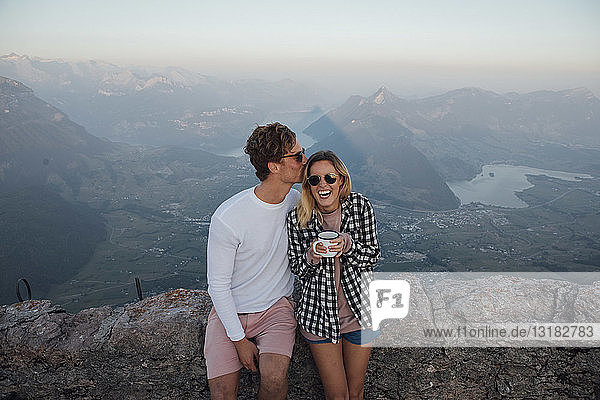 Schweiz,  Grosse Mythen,  glückliches junges Paar auf einer Wanderung mit Pause bei Sonnenaufgang