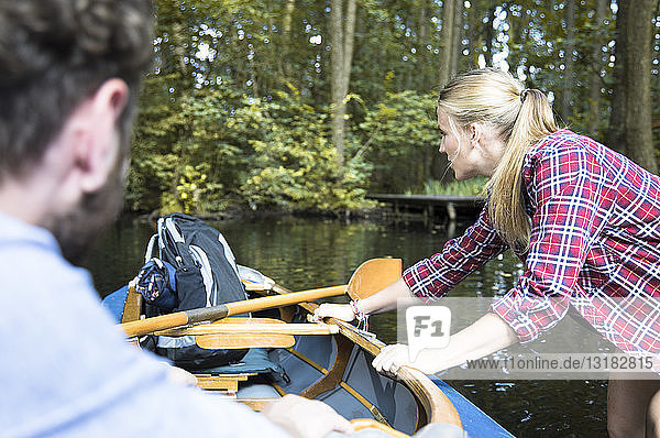 Junge Frau zieht Kanu auf einem Waldbach mit Mann