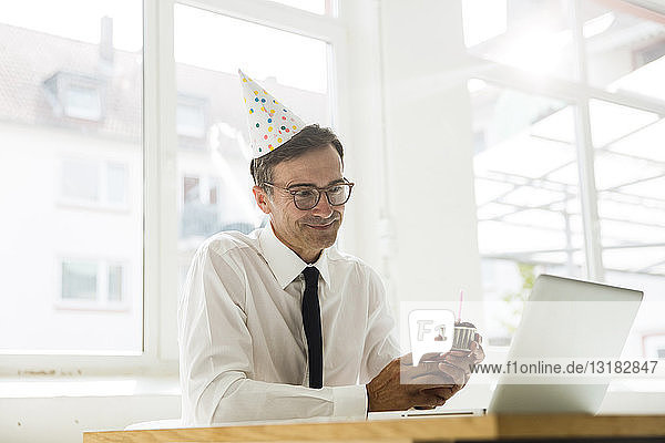 Geschäftsmann mit Laptop feiert Geburtstag im Amt