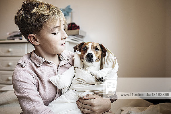 Boy with Jack Russel Terrier wrapped in blanket