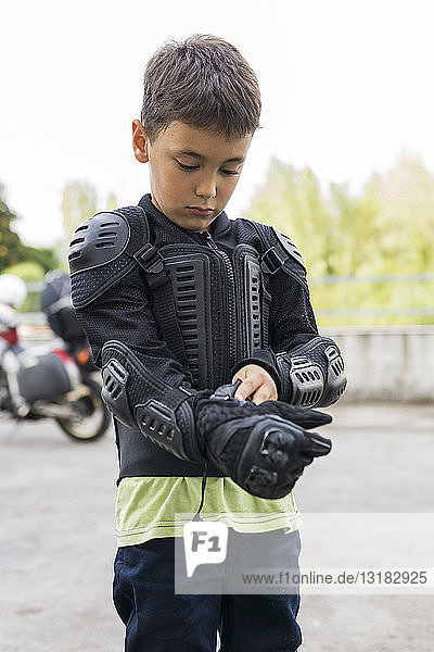 Boy putting on protective clothing preparing for a motorbike trip