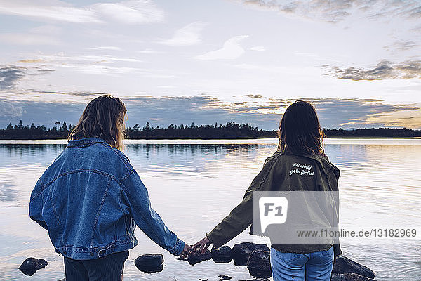 Girl friends looking at Lake Inari Finland  holding hands