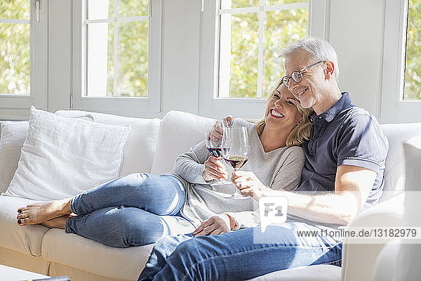 Reifes Paar entspannt sich auf der Couch bei Rotwein und hat Spaß