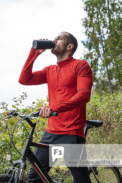 Athlete mountainbiking in nature  taking a break  drinking water