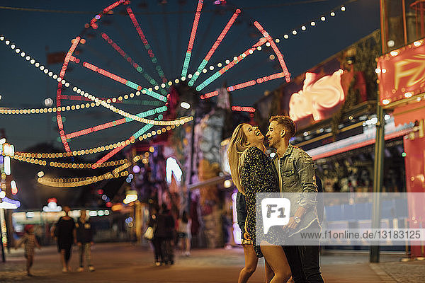 Happy young couple embracing and kissing at a funfair